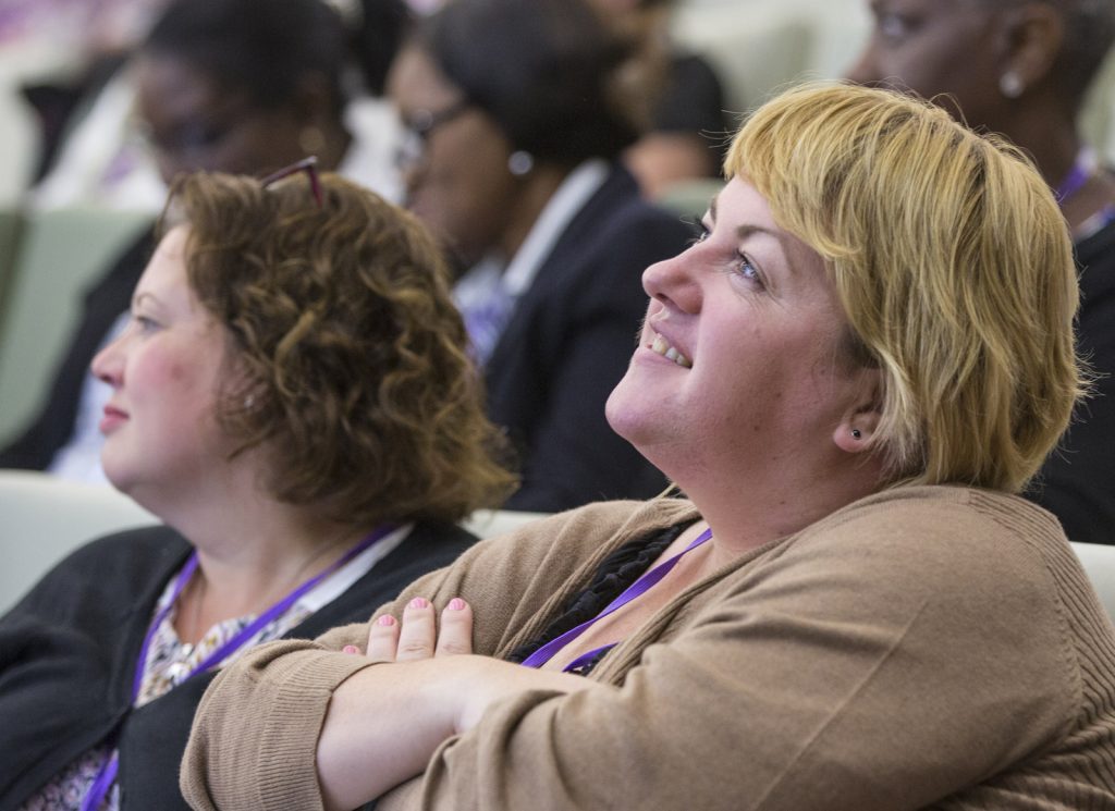A young woman at a conference listens to a speaker