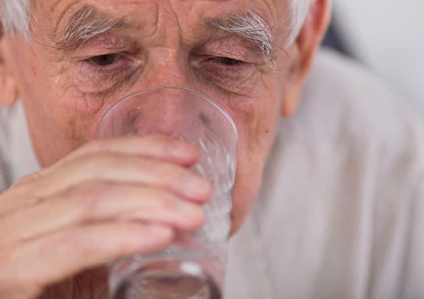 An old man drinking water