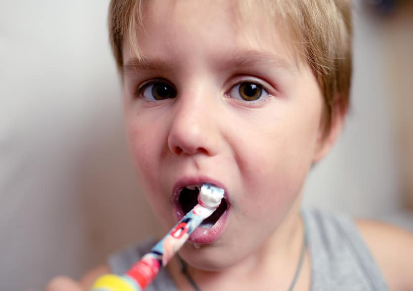 A young boy about 7 brushing his teeth